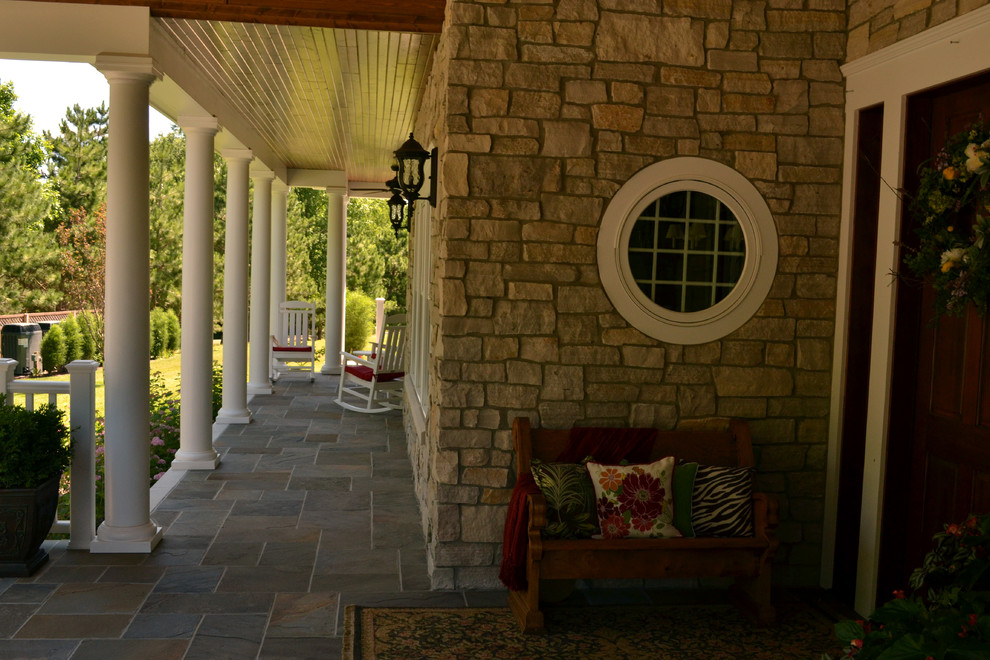 Esempio di un portico tradizionale davanti casa con pavimentazioni in pietra naturale e un tetto a sbalzo