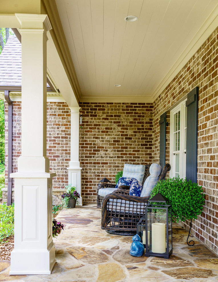 Exemple d'un porche d'entrée de maison avant chic de taille moyenne avec des pavés en pierre naturelle et un auvent.