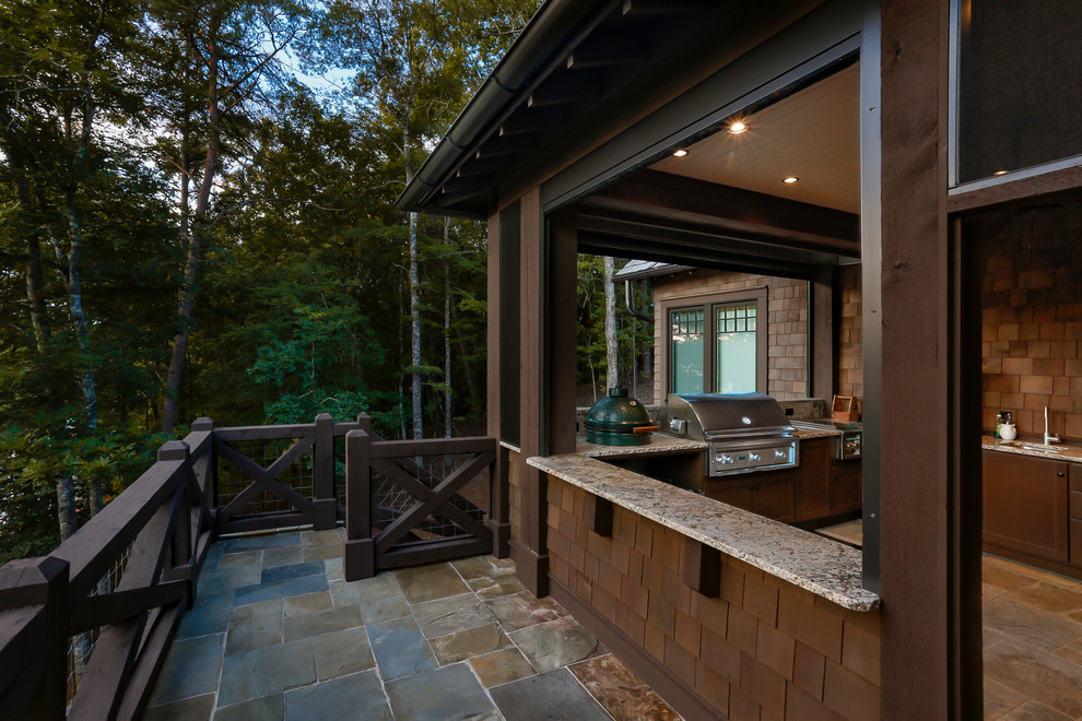 Cette photo montre un grand porche d'entrée de maison arrière bord de mer avec une cuisine d'été, des pavés en pierre naturelle et une extension de toiture.