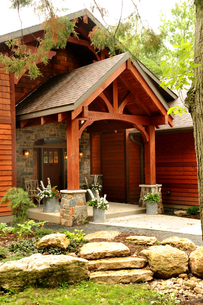 Réalisation d'un porche d'entrée de maison avant chalet de taille moyenne avec une dalle de béton et une extension de toiture.