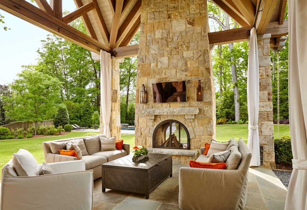 Idées déco pour un grand porche d'entrée de maison arrière montagne avec une cheminée, des pavés en pierre naturelle et une extension de toiture.