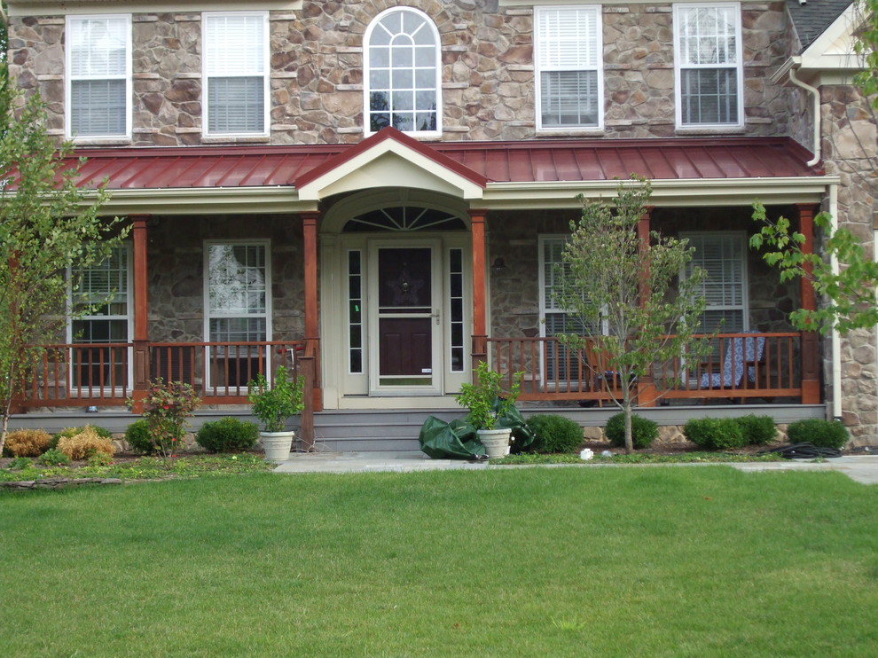 Cette image montre un grand porche d'entrée de maison avant chalet avec une extension de toiture et une terrasse en bois.