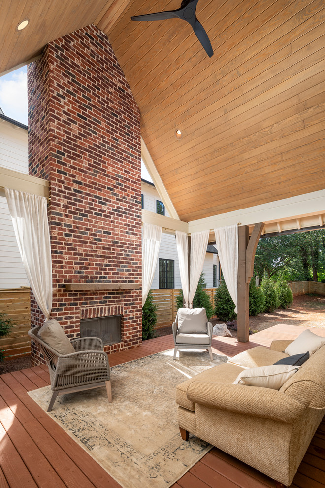 Cette photo montre un grand porche d'entrée de maison latéral chic avec une cheminée et une extension de toiture.