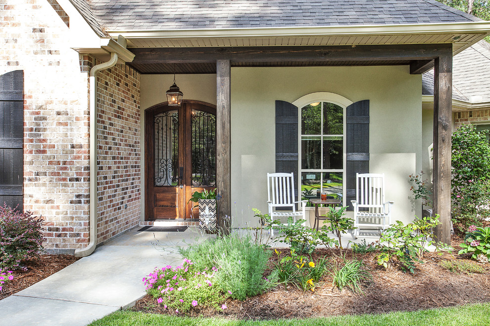 This is an example of a small traditional concrete front porch design in New Orleans with a roof extension.