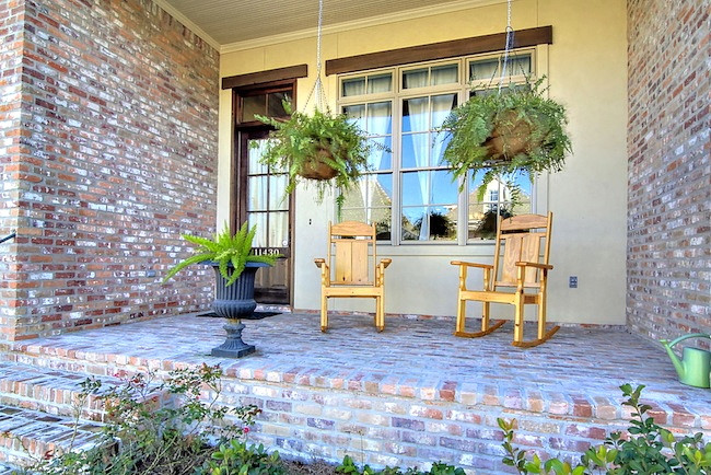 Medium sized traditional front veranda in New Orleans with brick paving.