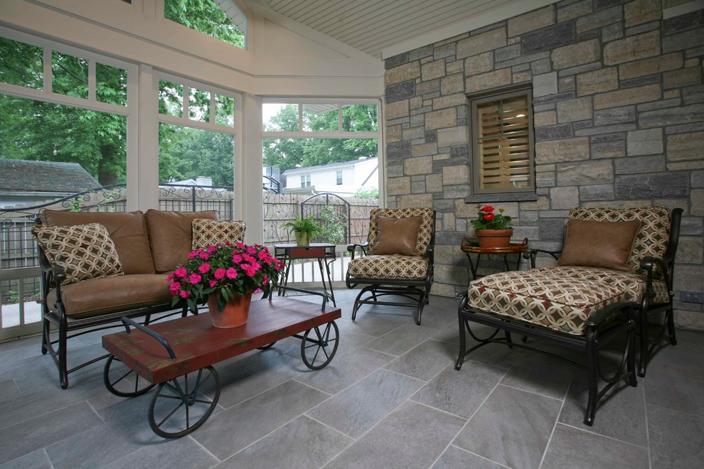 Bild på en mellanstor amerikansk innätad veranda på baksidan av huset, med naturstensplattor och takförlängning