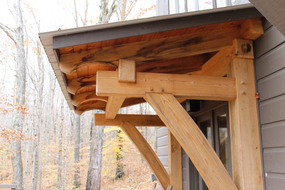 Réalisation d'un porche d'entrée de maison arrière craftsman de taille moyenne avec une terrasse en bois et une extension de toiture.