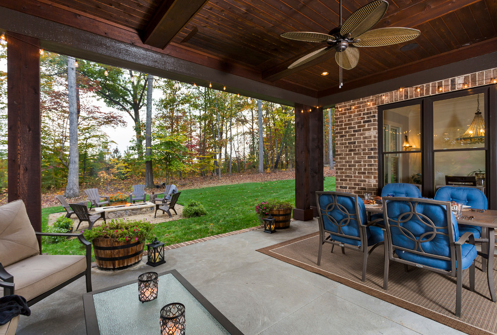 Cette photo montre un porche d'entrée de maison arrière craftsman avec un foyer extérieur, une dalle de béton et une extension de toiture.