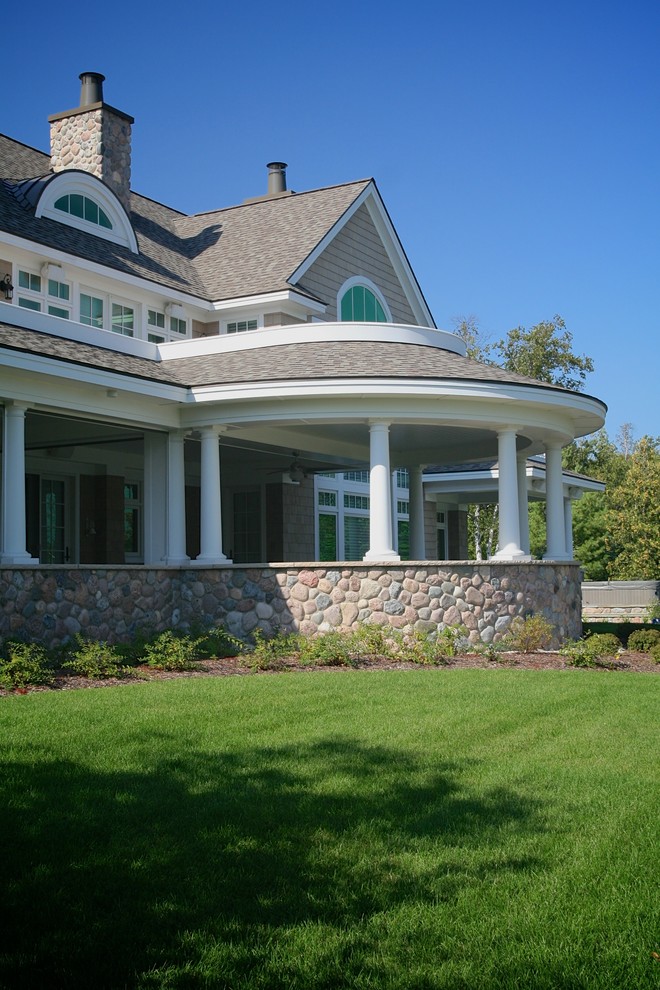 Пример оригинального дизайна: большая веранда на заднем дворе в стиле неоклассика (современная классика) с покрытием из каменной брусчатки и навесом