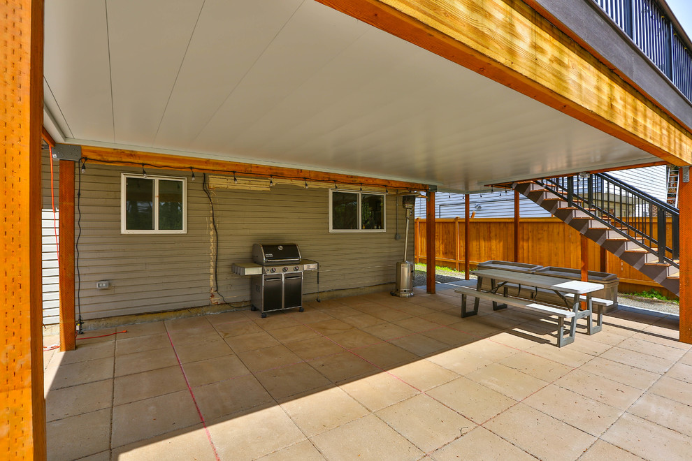 Immagine di un grande portico american style dietro casa con piastrelle e un tetto a sbalzo