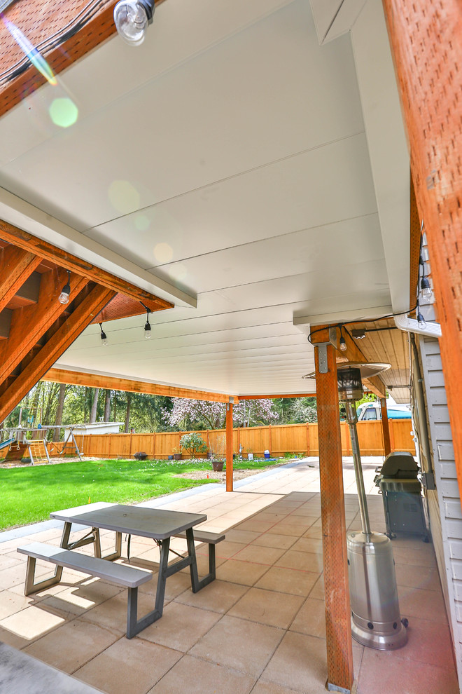 Aménagement d'un grand porche d'entrée de maison arrière craftsman avec du carrelage et une extension de toiture.