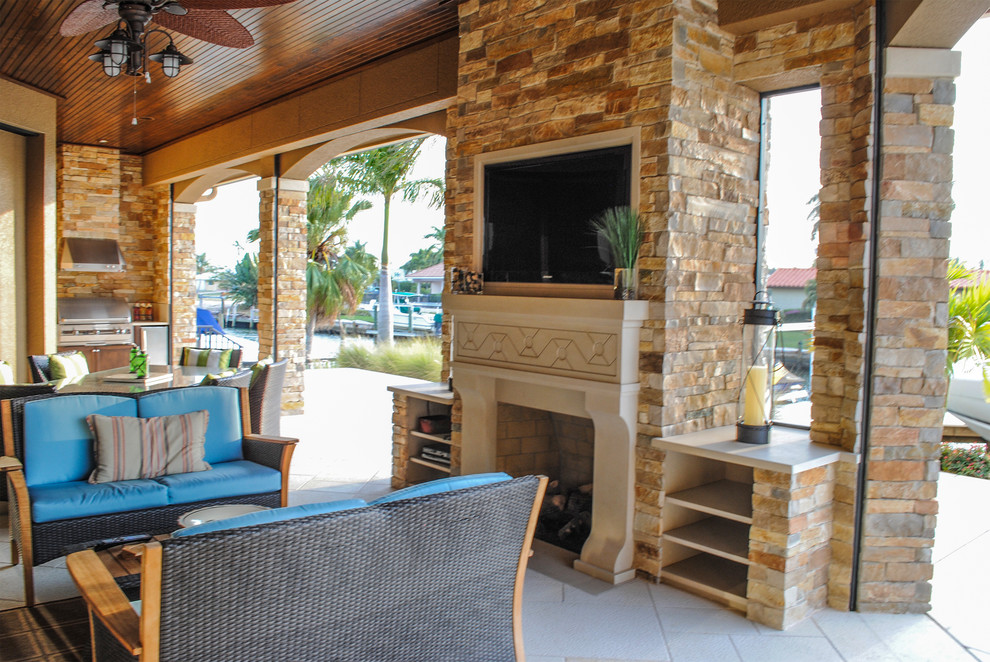 Tuscan stone back porch photo in Miami with a fire pit and a roof extension