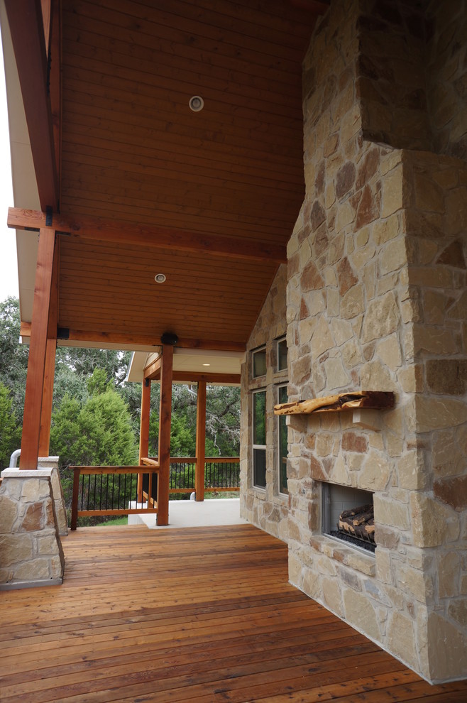 Foto på en stor lantlig veranda på baksidan av huset, med en öppen spis, trädäck och takförlängning