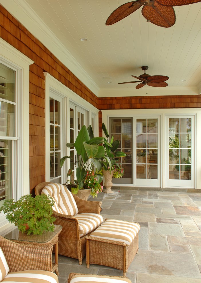Exemple d'un porche avec des plantes en pot arrière bord de mer de taille moyenne avec des pavés en pierre naturelle et une extension de toiture.