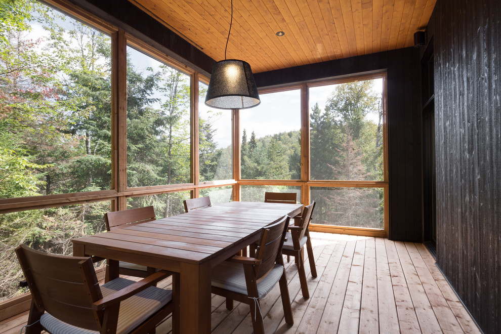 Réalisation d'un porche d'entrée de maison latéral chalet de taille moyenne avec une moustiquaire, une terrasse en bois et une extension de toiture.