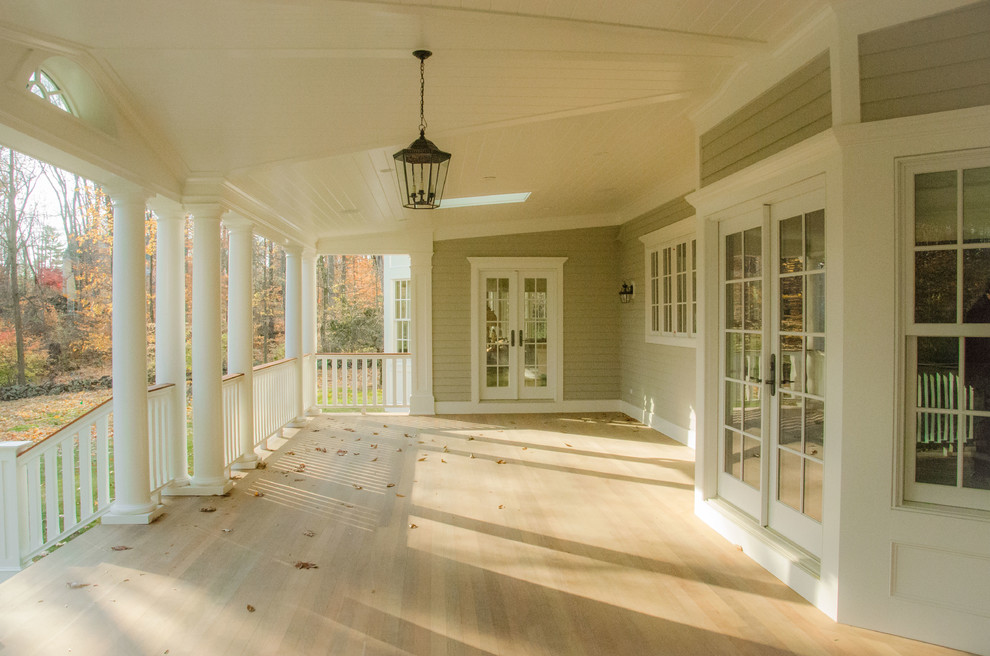 Idée de décoration pour un grand porche d'entrée de maison arrière tradition avec un foyer extérieur, une extension de toiture et une terrasse en bois.