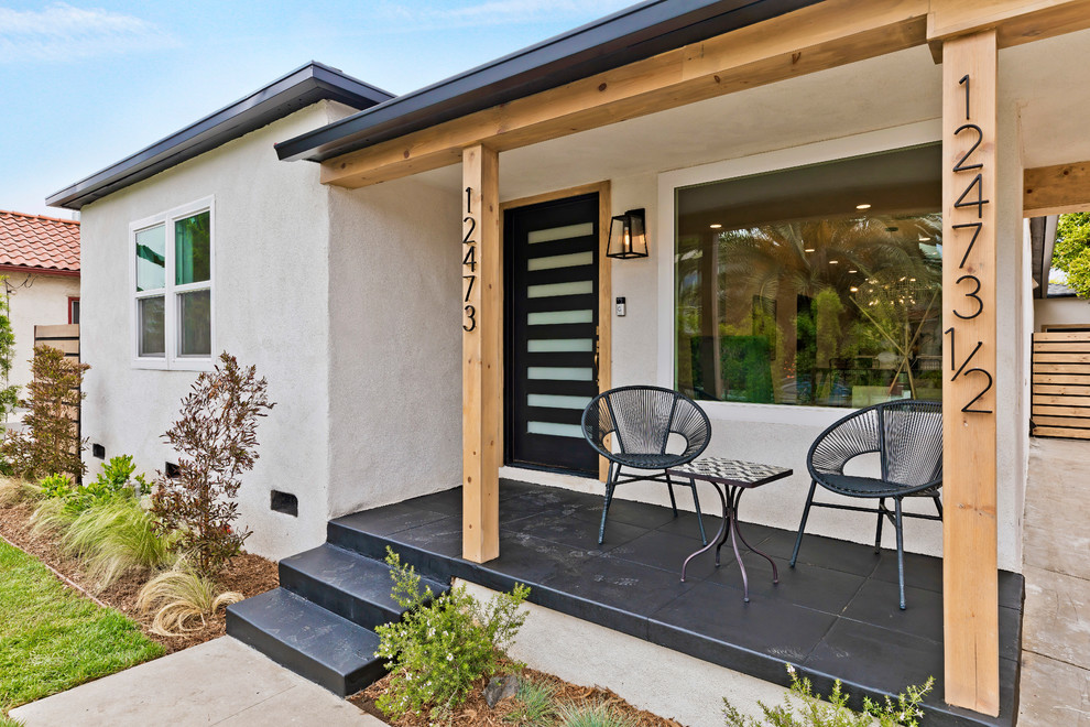 Inspiration for a contemporary front veranda in Los Angeles with tiled flooring and a roof extension.