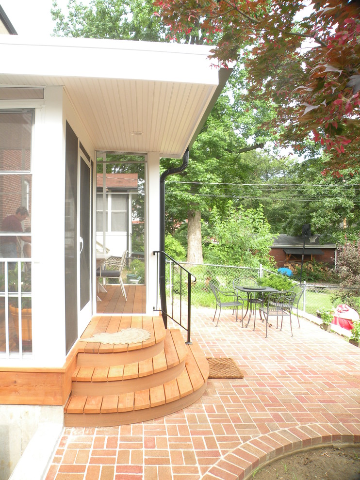 Inredning av en modern innätad veranda på baksidan av huset, med marksten i tegel och takförlängning