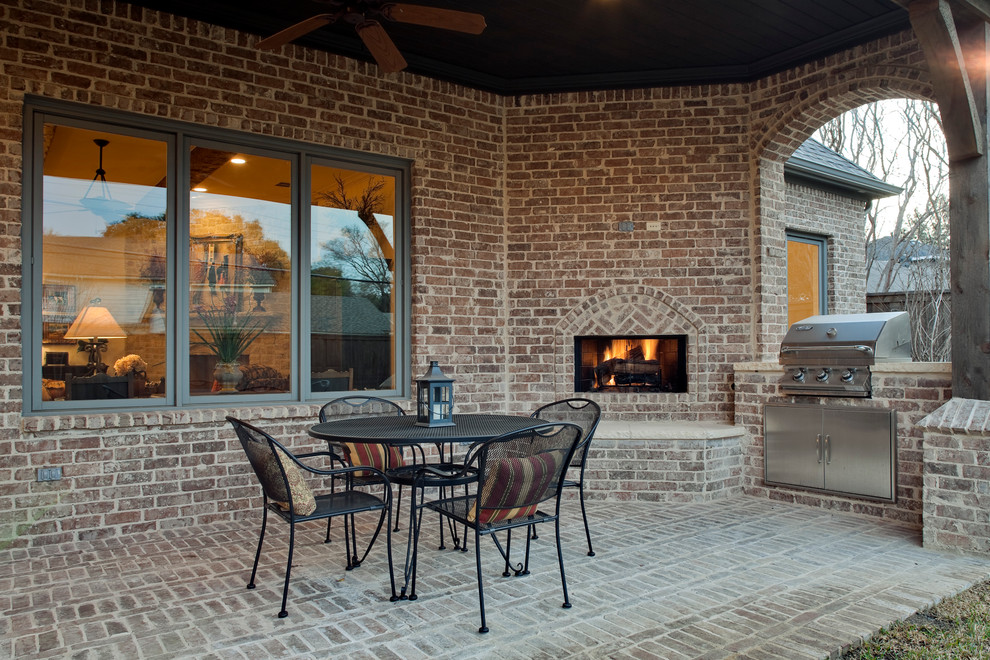 Foto di un patio o portico chic di medie dimensioni e dietro casa con un focolare, pavimentazioni in mattoni e un tetto a sbalzo