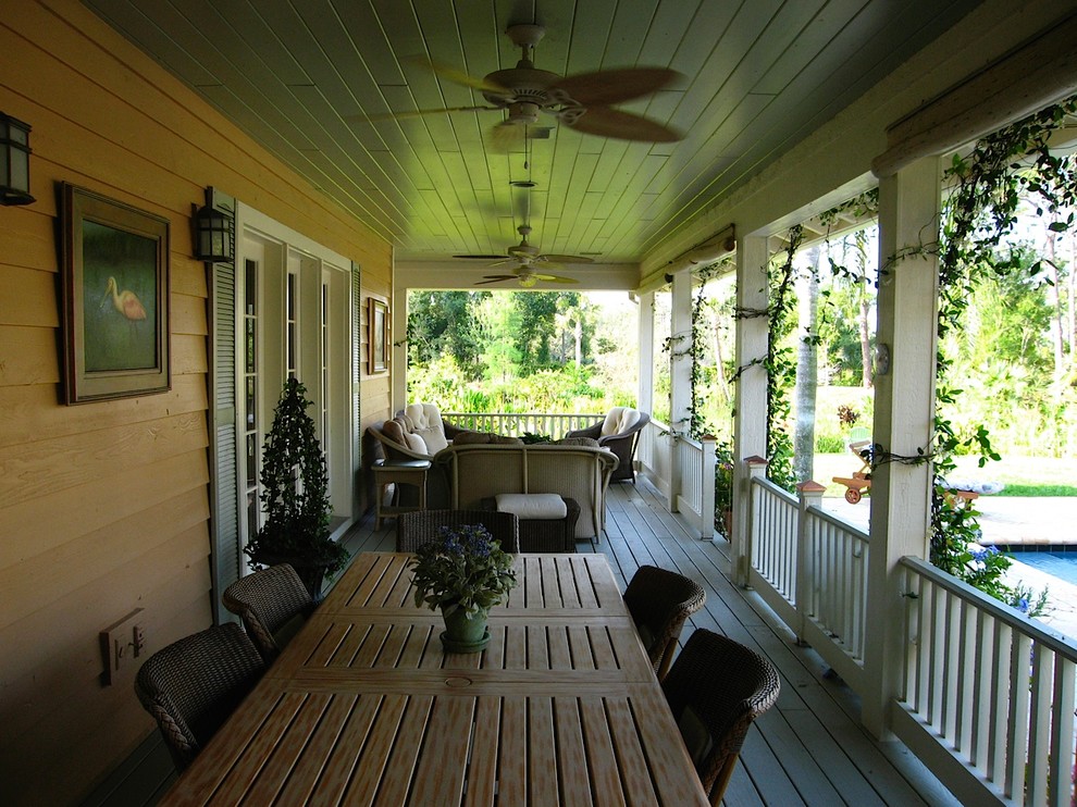 Idées déco pour un grand porche d'entrée de maison arrière campagne avec une extension de toiture et une terrasse en bois.