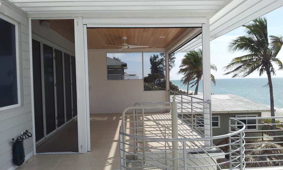 Immagine di un portico costiero di medie dimensioni e dietro casa con un portico chiuso e un tetto a sbalzo