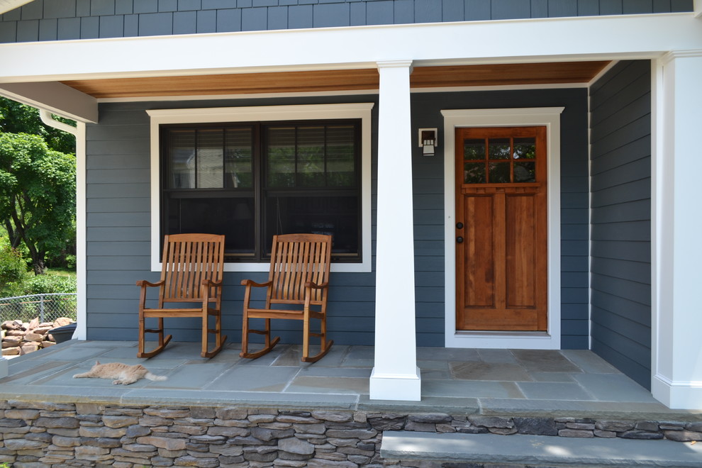 Immagine di un portico american style di medie dimensioni e davanti casa con pavimentazioni in pietra naturale e un tetto a sbalzo