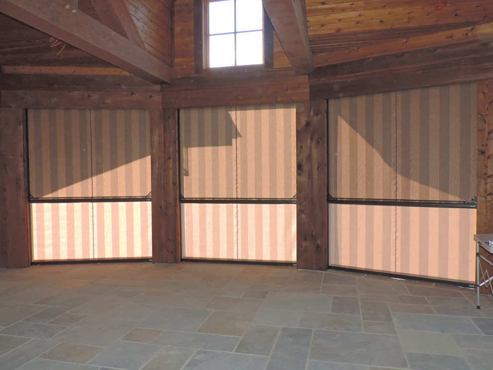 Idée de décoration pour un très grand porche d'entrée de maison arrière chalet avec une moustiquaire, une extension de toiture et des pavés en pierre naturelle.
