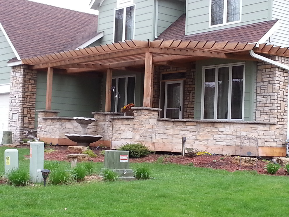 This is an example of a mid-sized rustic stone front porch design in Minneapolis with a pergola.