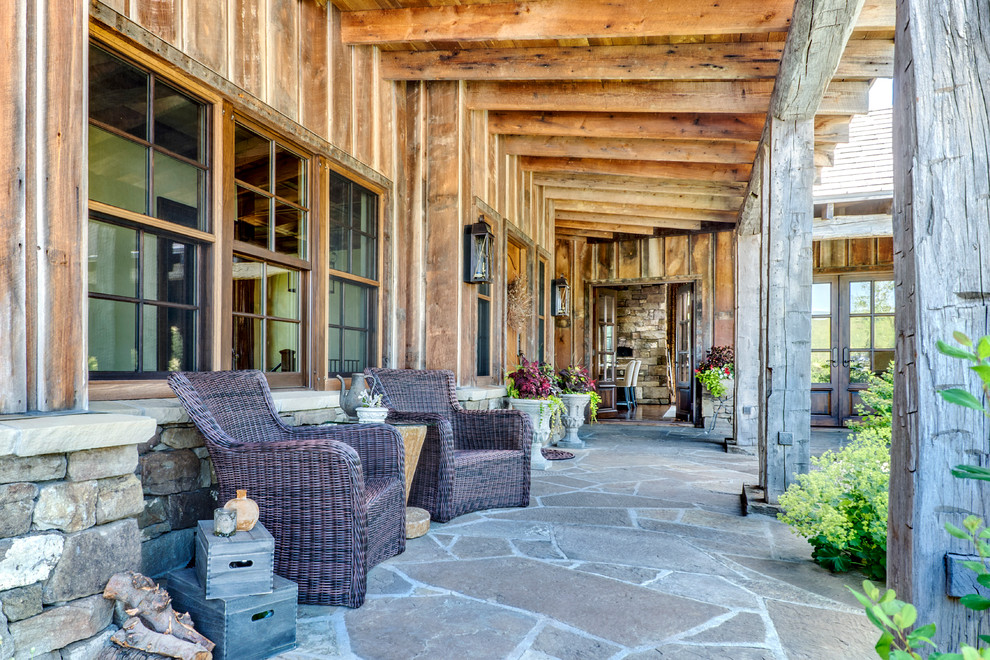 Große, Überdachte Rustikale Veranda hinter dem Haus mit Natursteinplatten in Sonstige