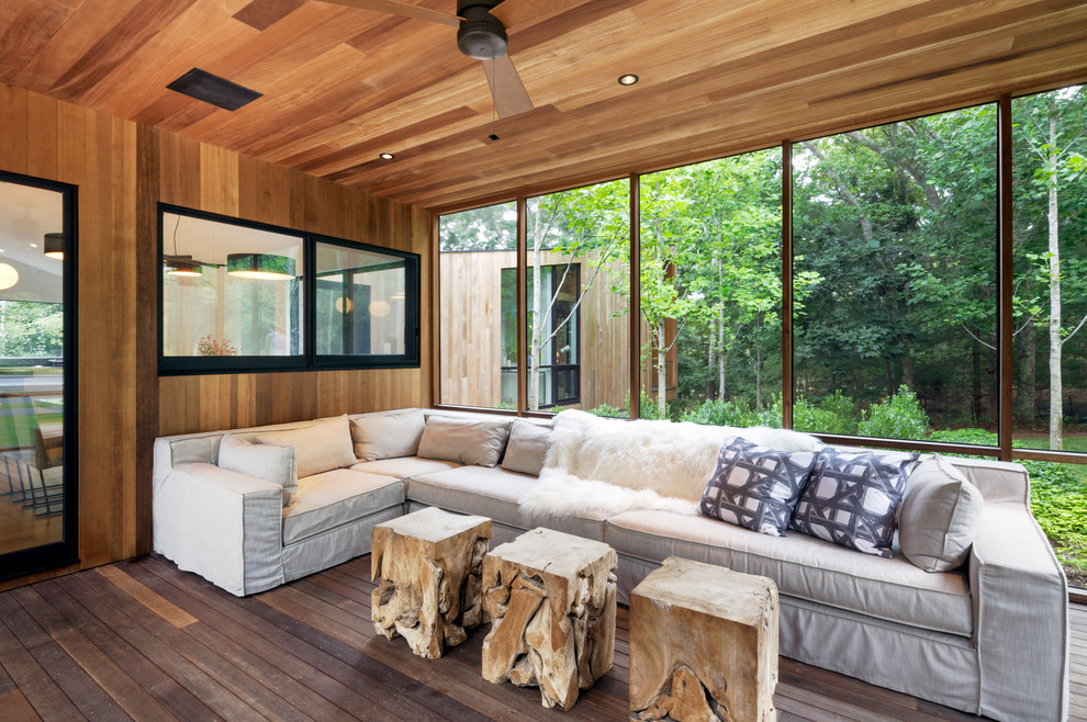 This is an example of a scandinavian screened-in porch design in New York with decking and a roof extension.