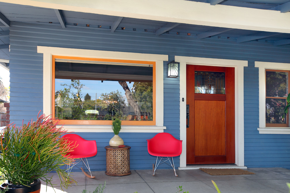 This is an example of an eclectic concrete porch design in Los Angeles with a roof extension.