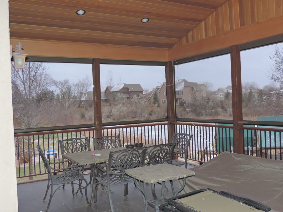 This is an example of a medium sized rustic side screened veranda in Minneapolis with concrete paving and a roof extension.
