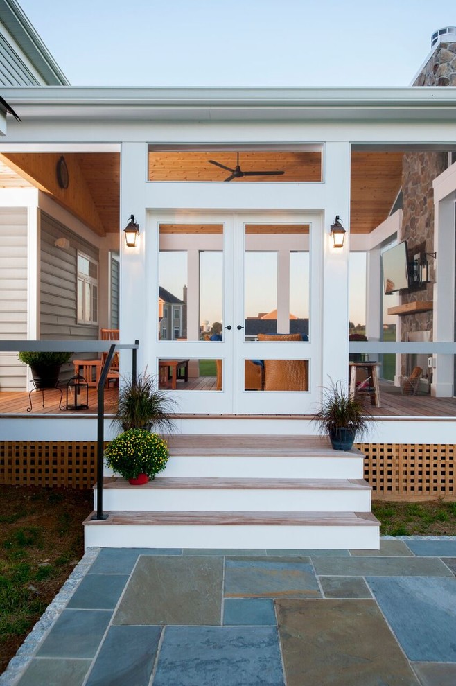 Idée de décoration pour un grand porche d'entrée de maison arrière chalet avec une moustiquaire, une terrasse en bois et une extension de toiture.