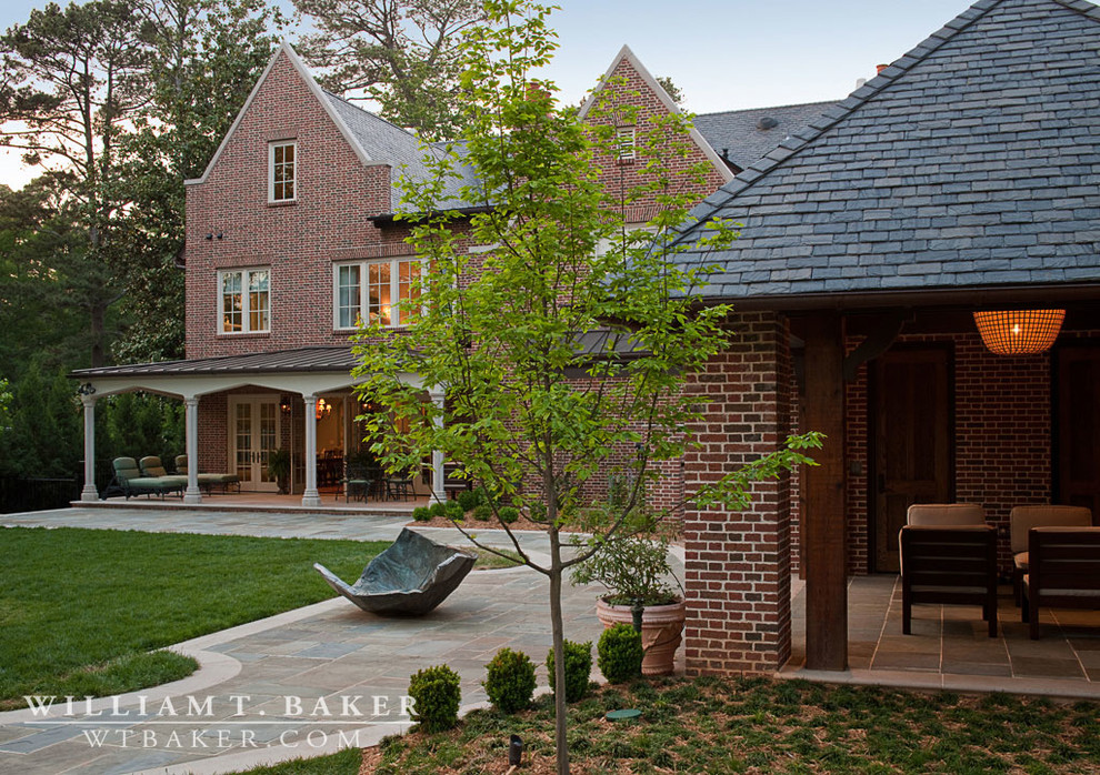 Idées déco pour un très grand porche d'entrée de maison arrière classique avec un foyer extérieur, des pavés en pierre naturelle et une extension de toiture.