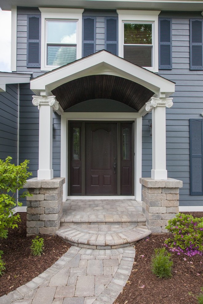 Small elegant stone front porch photo in Chicago with a roof extension