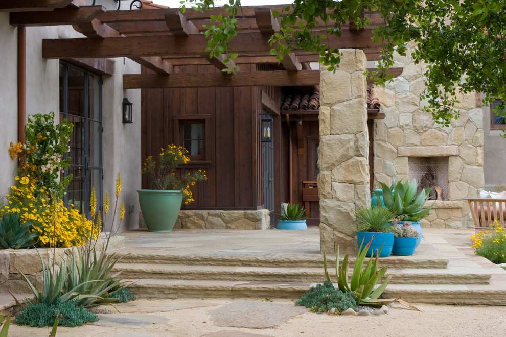 Modelo de terraza mediterránea en patio delantero con adoquines de piedra natural y pérgola