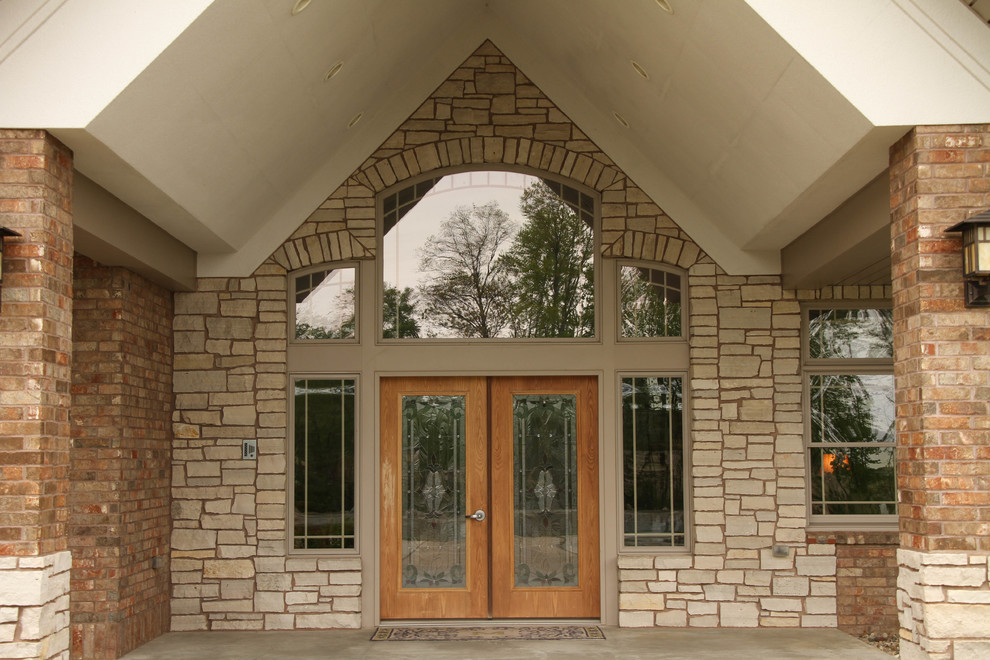 Cette image montre un très grand porche d'entrée de maison avant chalet avec une dalle de béton et une extension de toiture.
