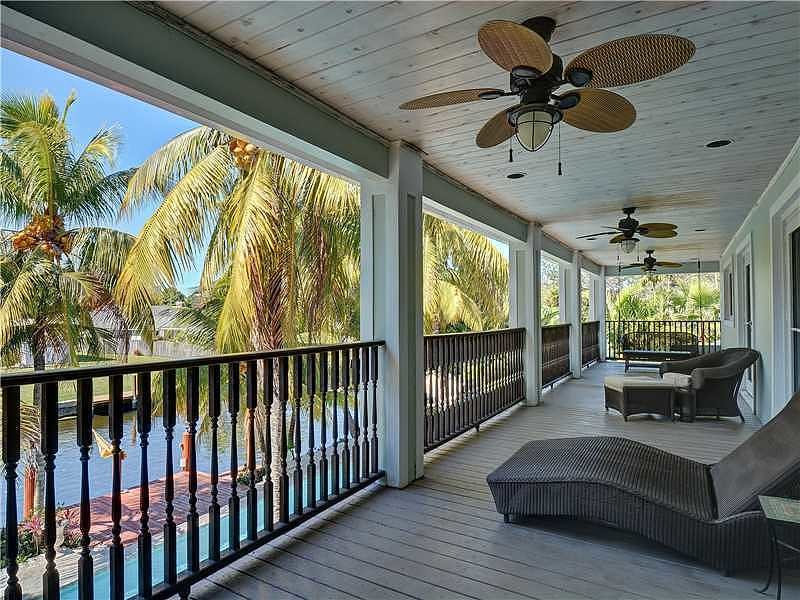 This is an example of a large tropical back porch design in Miami with decking and a roof extension.