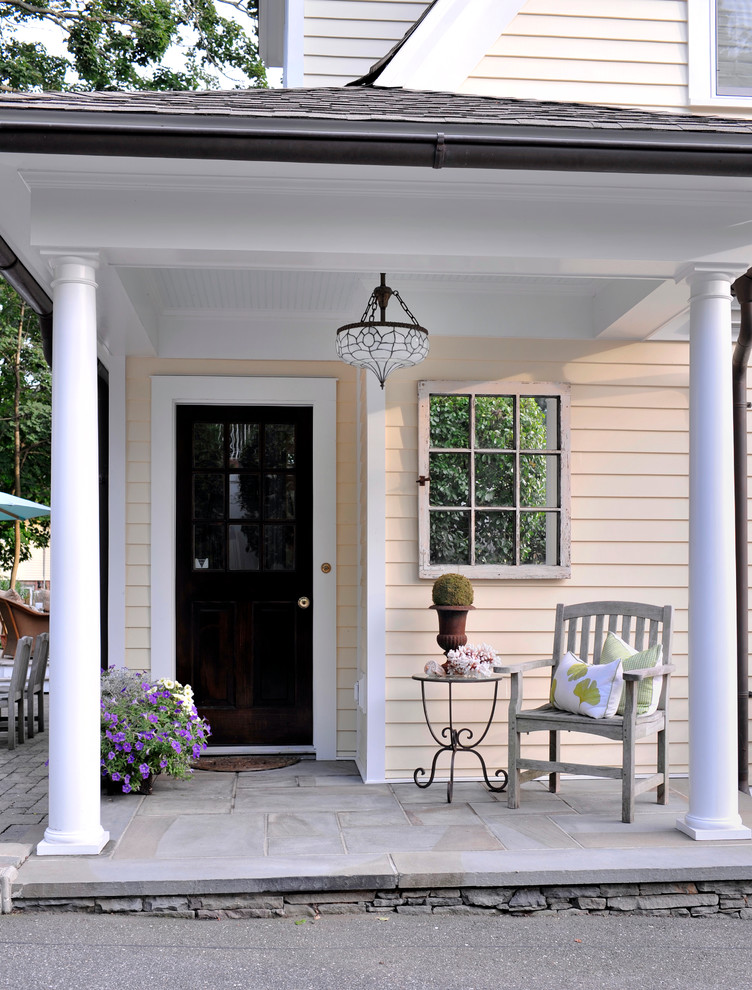 Inredning av en klassisk mellanstor veranda längs med huset, med naturstensplattor och takförlängning