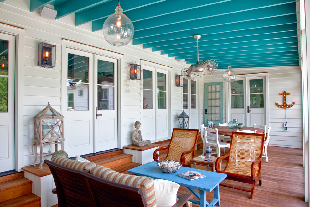 Exemple d'un porche d'entrée de maison bord de mer avec une terrasse en bois et une extension de toiture.
