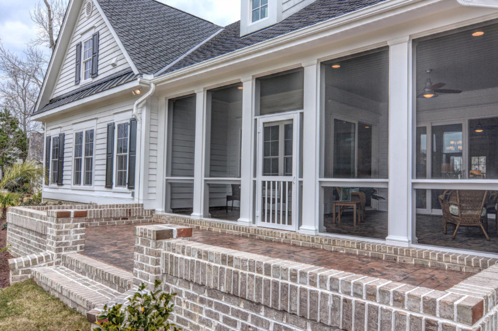 Idées déco pour un grand porche d'entrée de maison arrière classique avec du béton estampé, une extension de toiture et une moustiquaire.