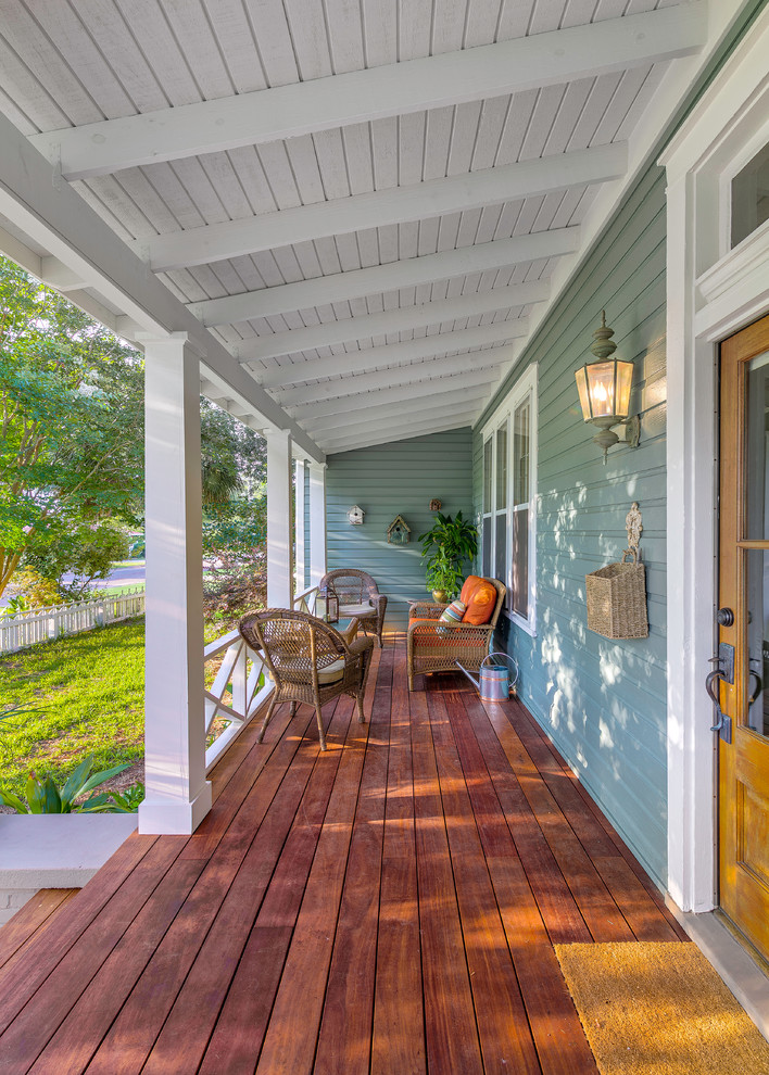 Cette photo montre un grand porche d'entrée de maison avant chic avec une terrasse en bois et une extension de toiture.