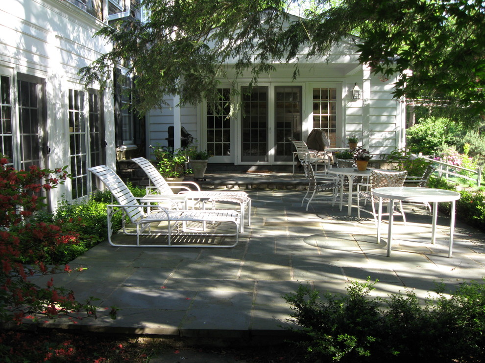 Photo of a large contemporary back patio in Philadelphia with natural stone paving and a roof extension.
