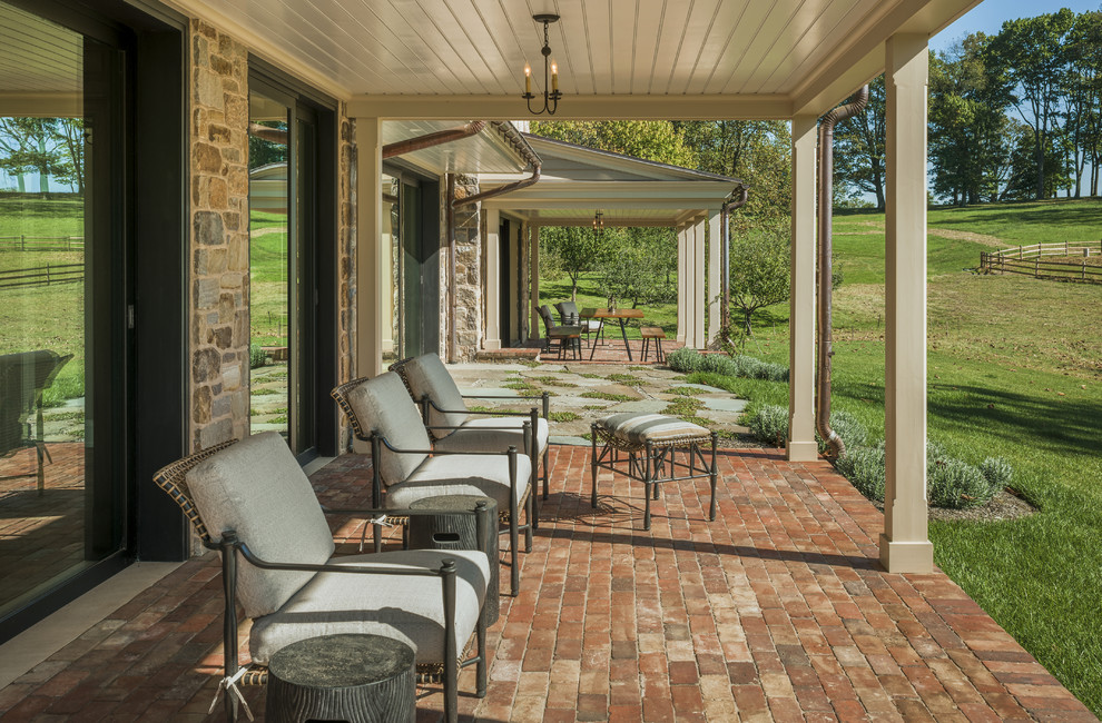 This is an example of a country brick side porch design in Philadelphia with a roof extension.