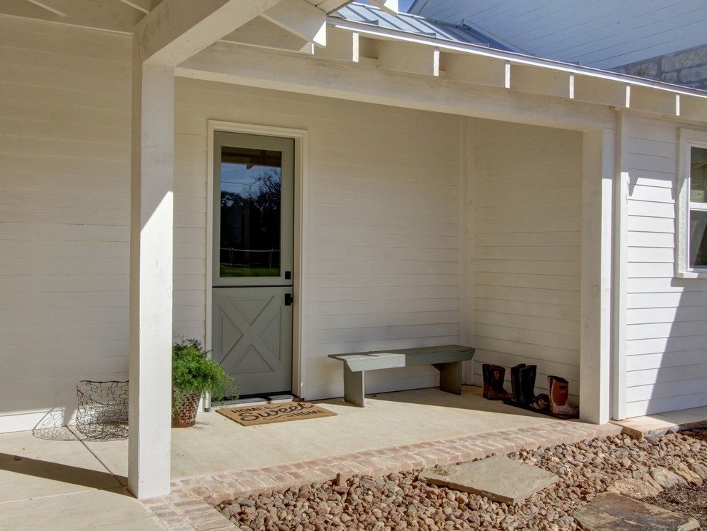 Aménagement d'un porche d'entrée de maison avant campagne avec des pavés en pierre naturelle et une extension de toiture.