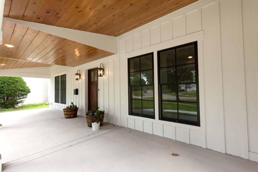 This is an example of a large farmhouse front veranda in Chicago with a roof extension, concrete paving and with columns.