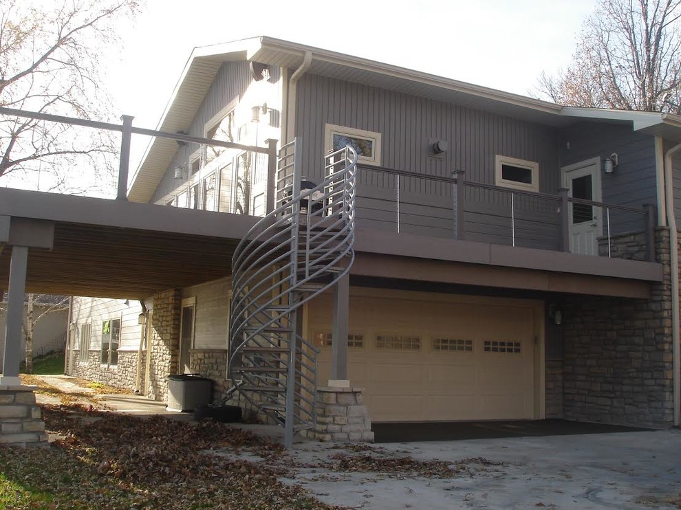Exempel på en stor amerikansk veranda på baksidan av huset, med trädäck och takförlängning