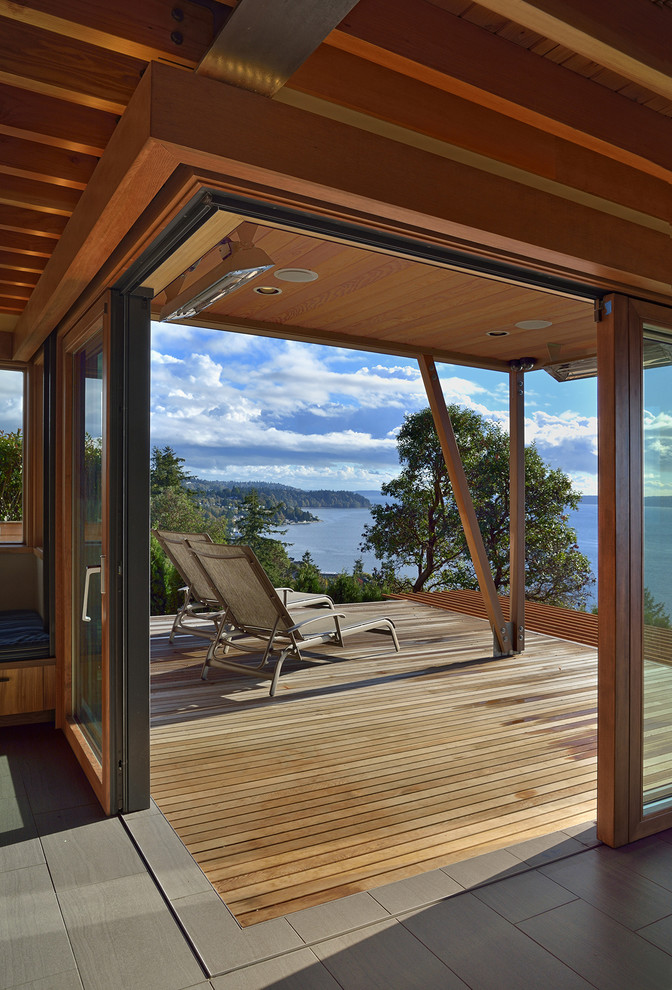 Idées déco pour un grand porche d'entrée de maison arrière contemporain avec une terrasse en bois.