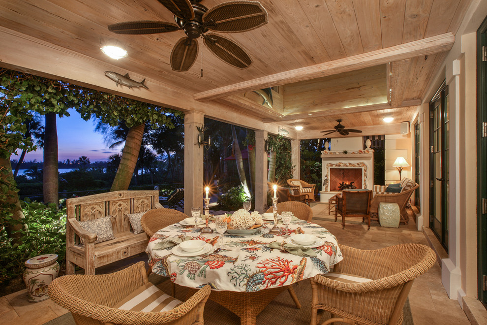 Immagine di un portico tropicale dietro casa con piastrelle, un tetto a sbalzo e con illuminazione
