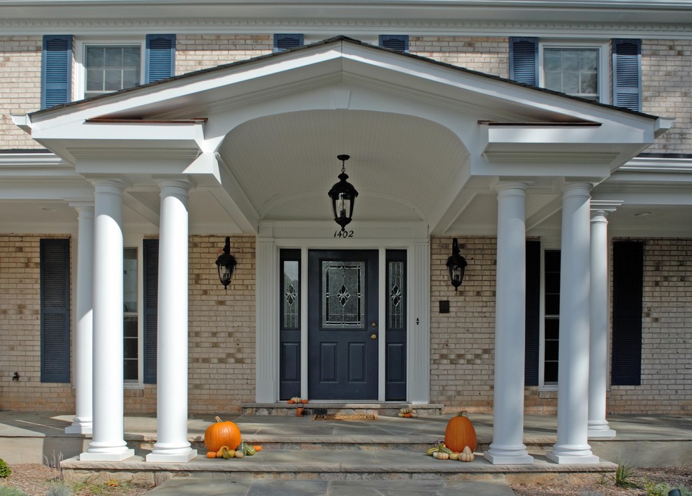 Mid-sized classic stone front porch idea in DC Metro with a roof extension